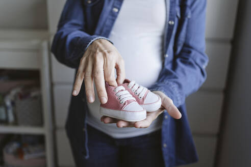 Schwangere Frau mit Babyschuhen zu Hause - EBBF05257