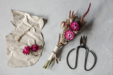 Studio shot of scissors, piece of paper and small bouquet of dried flowers - EVGF03968