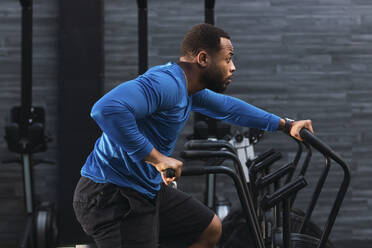 Determined athlete exercising on airbike in gym - PNAF02856