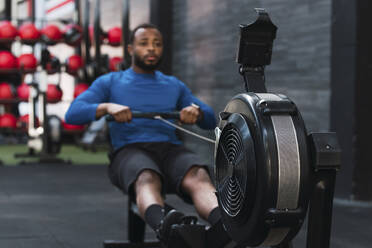 Sportler beim Training auf einem Rudergerät im Fitnessstudio - PNAF02857