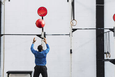 Sportler beim Training mit einem Medizinball im Fitnessstudio - PNAF02883