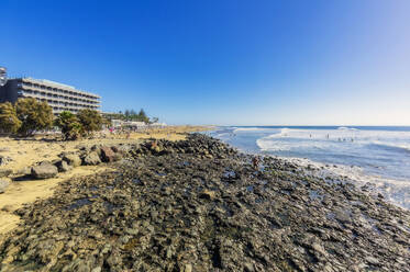 Spanien, Gran Canaria, Maspalomas, Felsiger Küstenstrand mit Ferienanlage im Hintergrund - THAF03011