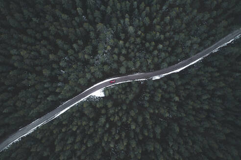 Luftaufnahme eines roten Autos auf einer kurvenreichen Waldstraße im Winter, Korvemaa, Harjumaa, Estland. - AAEF13986