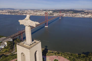 Luftaufnahme der Brücke des 25. April und des Cristo Rei (Christus der König) bei Sonnenuntergang über dem Fluss Tejo, Almada, Lissabon, Portugal. - AAEF14020