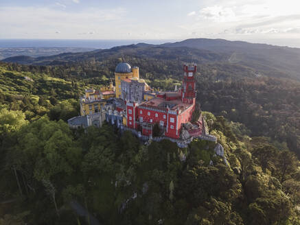 Luftaufnahme des Pena-Palastes, eines farbenfrohen romantischen Schlosses auf einem Hügel während eines wunderschönen Sonnenuntergangs, Sintra, Lissabon, Portugal. - AAEF14024