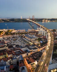 Aerial view of April 25th bridge with Christ the King statue (Cristo Rei) in background at sunset, view of Lisbon skyline at night, Alcântara, Lisbon, Portugal. - AAEF14027