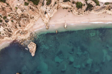 Luftaufnahme von oben auf die wilde Küste in der Nähe von Praia da Marinha mit kleinen paradiesischen Stränden bei Sonnenaufgang, Lagoa, Algarve-Region, Portugal. - AAEF14029