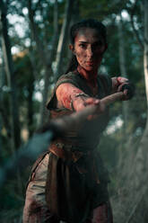 Tapfere Frau im Wikingerkostüm steht und streckt die Hand mit einem Speer während einer Schlacht im Wald aus - ADSF33474