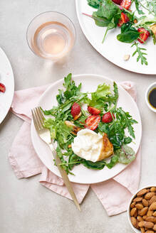 Draufsicht auf einen Salat mit Rucola, gegrilltem Hähnchen, frischen Erdbeeren und Burrata-Käse, garniert mit gehobelten Mandeln. Ungewöhnliche Geschmackskombination - ADSF33477