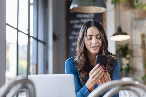 Freiberufler mit Laptop und Smartphone im Cafe - EIF03205