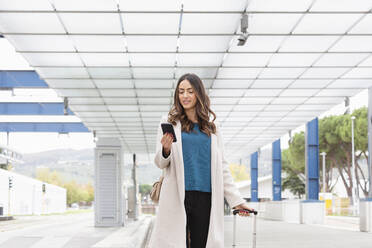 Young businesswoman using smart phone and walking on footpath - EIF03233