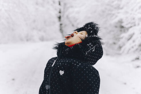 Girl trying to catch snow on tongue in winter - OMIF00516