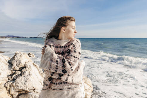 Teenager-Mädchen im Pullover umarmt sich selbst am Strand - OMIF00527