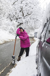 Mann mit Schneeschaufel auf der Straße stehend im Winter - OMIF00534