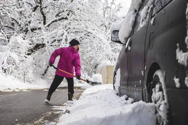 Mann schaufelt im Winter Schnee ums Auto - OMIF00536