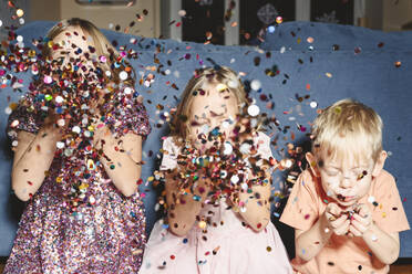 Siblings blowing confetti at home - EYAF01905