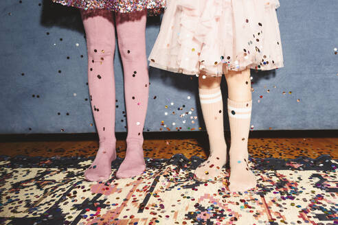 Legs of girls standing on floor covered with confetti - EYAF01906