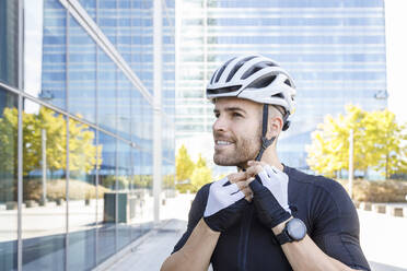 Junger Mann befestigt Fahrradhelm - IFRF01499