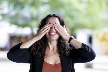 Happy businesswoman covering eyes with hands - WPEF05761