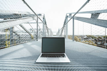 Laptop over metal floor on office balcony - JOSEF06612