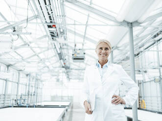 Happy scientist with hand on hip in industry - JOSEF06634