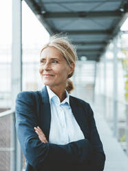 Smiling businesswoman with arms crossed in office - JOSEF06646