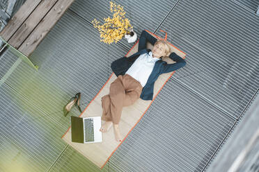 Businesswoman lying on desk with laptop in office - JOSEF06654