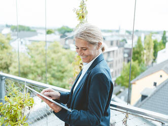 Smiling businesswoman using tablet PC in office - JOSEF06658