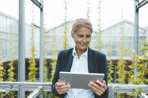 Lächelnde Wissenschaftlerin mit digitalem Tablet im Gartencenter - JOSEF06662