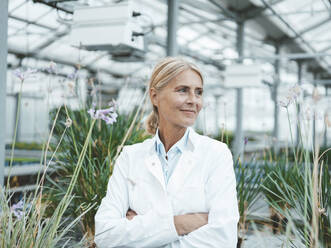 Thoughtful agronomist with arms crossed in garden center - JOSEF06693