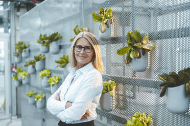 Confident scientist with arms crossed in plant nursery - JOSEF06730