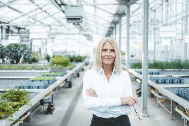 Confident scientist with arms crossed in plant nursery - JOSEF06737