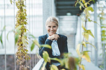 Happy scientist with hand on chin at greenhouse - JOSEF06768