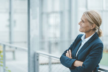 Happy businesswoman with arms crossed in office - JOSEF06772