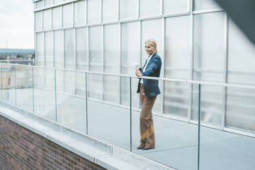 Contemplative businesswoman standing on office balcony - JOSEF06781
