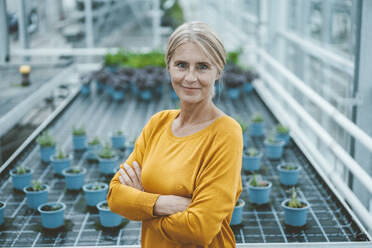 Confident biologist with arms crossed in plant nursery - JOSEF06815