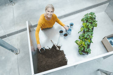 Lächelnde Agronomin mit Töpfen und Erde im Gartencenter - JOSEF06823