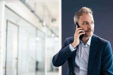 Geschäftsmann, der im Büro mit seinem Handy telefoniert - JOSEF06858