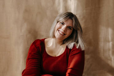 Happy curvy woman with blond hair in front of brown backdrop - TCEF02201
