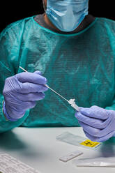 Anonymous doctor with medical gloves putting the swab into the extraction tube with liquid for a coronavirus test in the clinic - ADSF33600