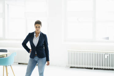 Confident businesswoman with hand on hip standing at office - GUSF06724