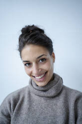 Frau in grauem Pullover lächelnd vor einer Wand - GUSF06749