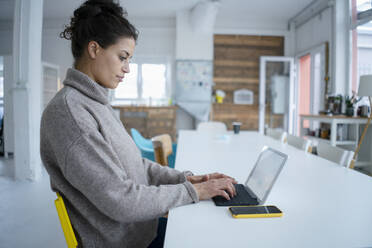 Busy freelancer using tablet PC sitting at desk in office - GUSF06751