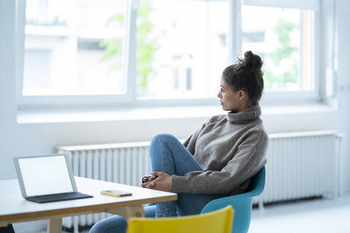 Nachdenkliche Frau sitzt am Tisch mit Tablet-PC und Smartphone - GUSF06756