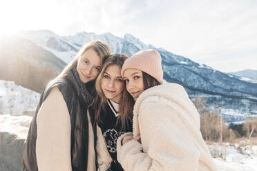 Freunde im Teenageralter umarmen sich vor einem Berg - OMIF00555