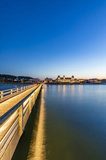 Deutschland, Mecklenburg-Vorpommern, Binz, Leere Seebrücke in der Abenddämmerung mit Kurhaus Binz im Hintergrund - WDF06765