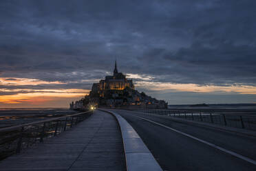 Frankreich, Normandie, Bewölkter Himmel über der Verbindungsbrücke zur Insel Mont-Saint-Michel in der Abenddämmerung - RUEF03508