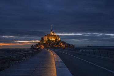 France, Normandy, Cloudy sky over bridge connecting Mont-Saint-Michel island at dusk - RUEF03510