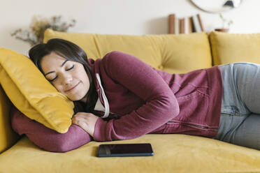 Young woman sleeping on sofa at home - XLGF02589