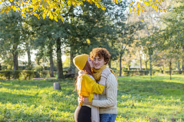 Woman kissing boyfriend on cheek at autumn park - EIF03287